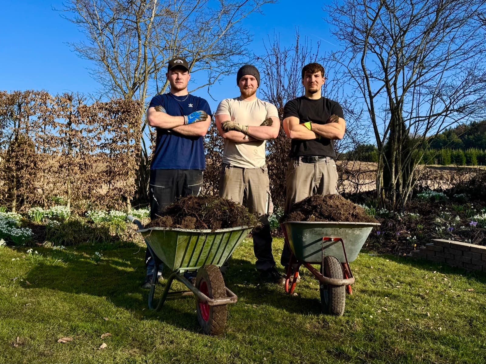 Das Heimathelfer-Team mit Schubkarren voller Grünschnitt im Garten